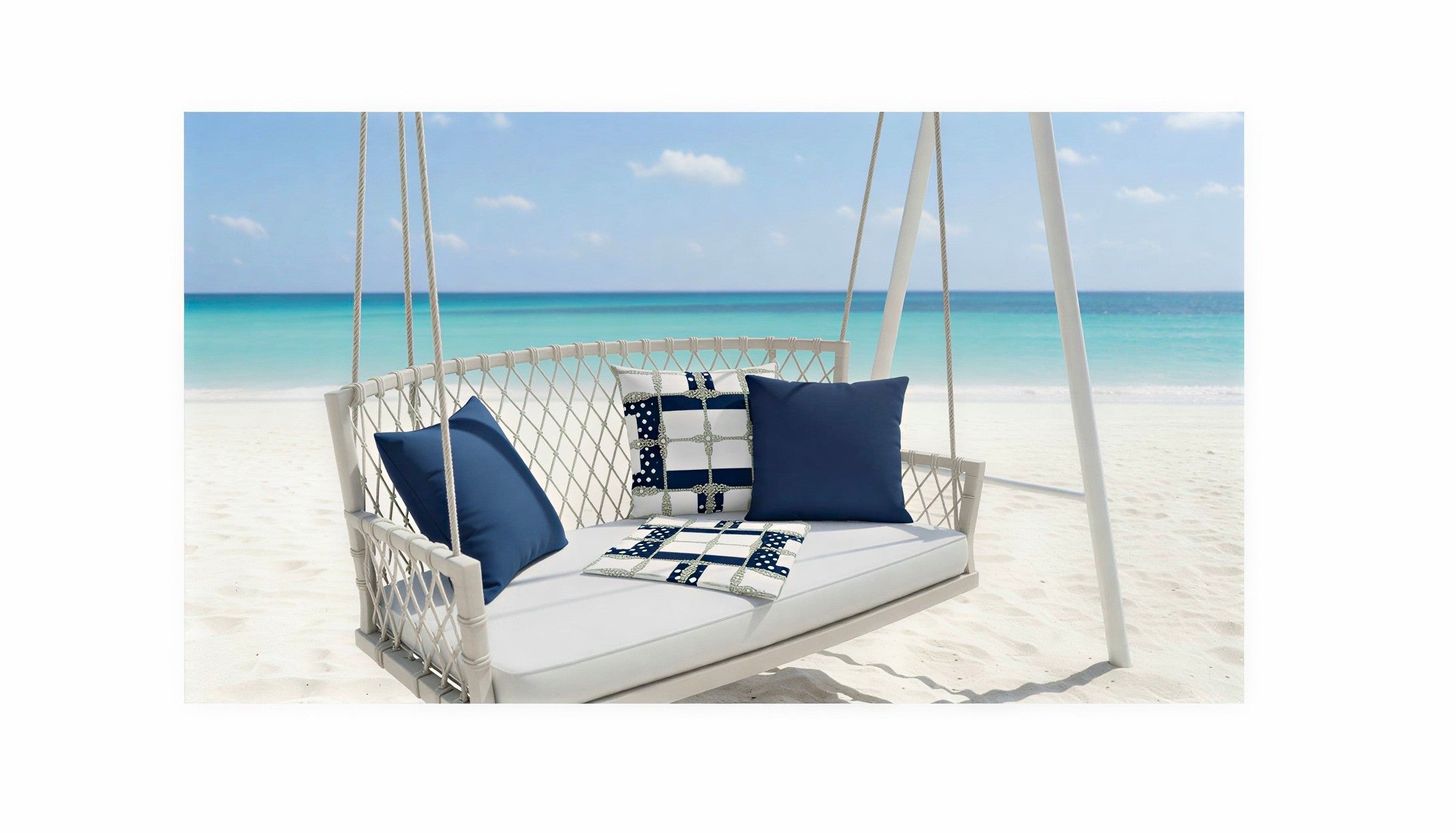 ARTEMI ARTELIA cushion collection styled on a white swing against a crystal-blue beach resort with white sand — sustainable artistry in every detail.