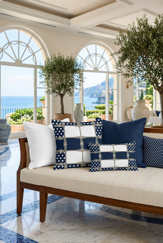 A square throw pillow featuring a navy blue and white geometric grid pattern with white polka dots on the side panels and ornate silver chain-link motifs dividing the center.