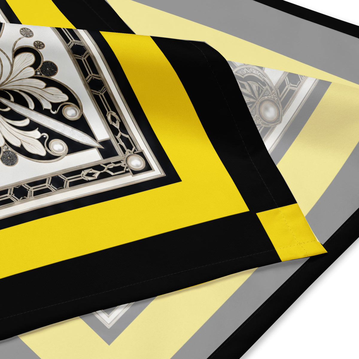 A square scarf corner featuring a bold Art Deco style design with a central black, white, and silver geometric motif, surrounded by a wide yellow border and a black outer border with yellow corner accents.
