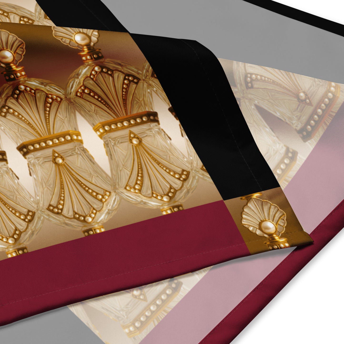 Close-up shot of a square scarf with a one-sided print, featuring double-hemmed edges in a silky-feel polyester material with a burgundy and gold accent pattern.