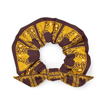 Brown recycled material scrunchie with decorative repeated gold ornate pattern on a white background