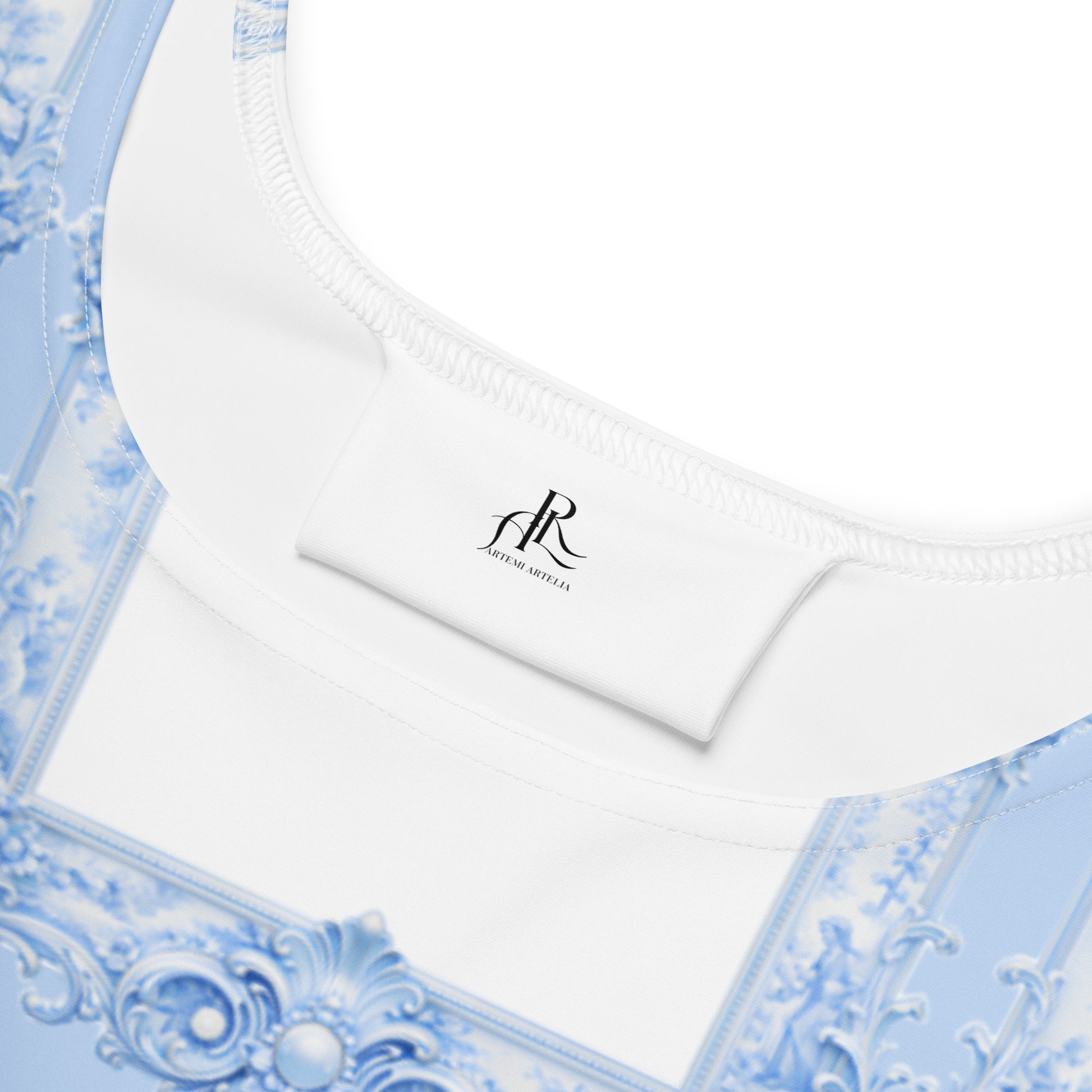 Close-up of the decorative neckline of a blue skater dress with ornate patterns and a visible brand label,  ARTEMI ARTELIA on a white background.
