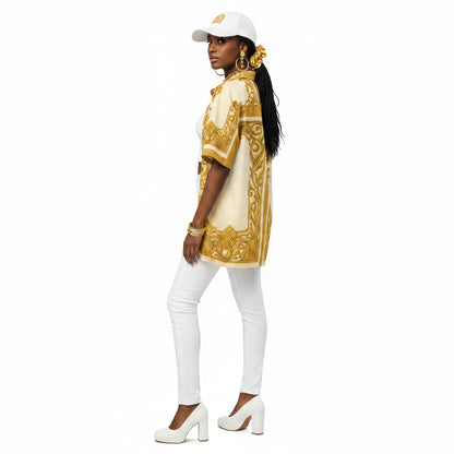 A woman shown from the back wearing a cream short-sleeve button-up shirt with a prominent gold baroque-style pattern, paired with black jeans and white sneakers, against a plain white background.