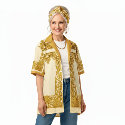 A woman modeling a short-sleeve button-front shirt jacket with a cream base and ornate gold western-style scrollwork pattern, worn over a white t-shirt and blue jeans against a plain white background.