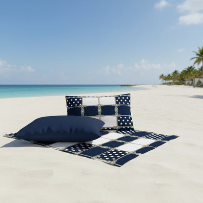 Decorative pillows featuring geometric pattern and navy and white polka dots placed at the beach against crystal blue ocean.