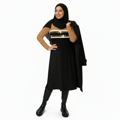 A hijab-wearing model in ARTEMI ARTELIA original designs — an A-line long sleeve midi dress in nude and black colour-block design featuring Egyptian Revival Art Deco Pharaoh motifs.